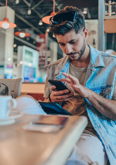 Portrait of man drink coffee at the airport while using mobile