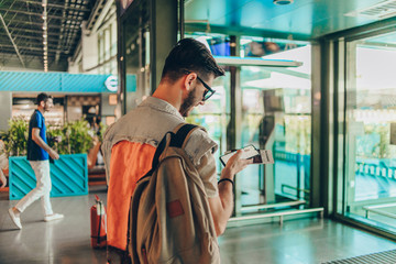 Man with backpack and passport in his hands walking in airport