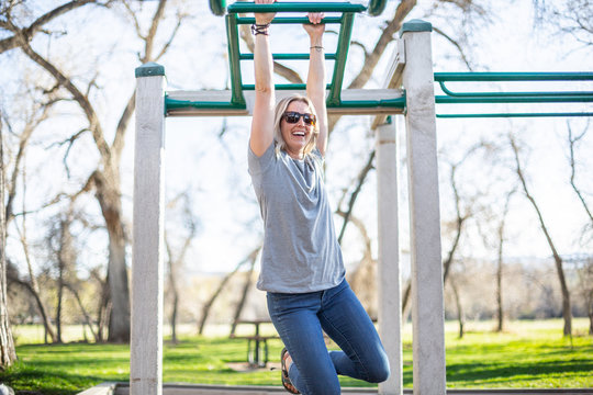 Woman hanging from monkey bars in a playground, United States