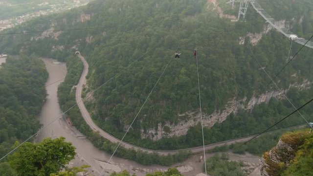  two mens fly on zipline over valley in Sochi Skypark