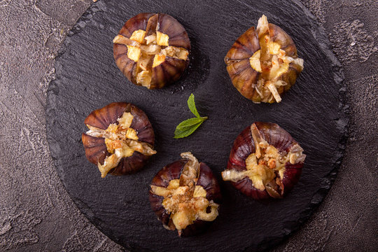 Ripe figs baked with cow's-milk cheese brie and camambert and sprinkled with bread crumbs decorated with mint leaves  on black stone background. Healthy eating concept. top view