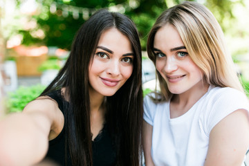 Two young beautiful women taking selfie in cafe