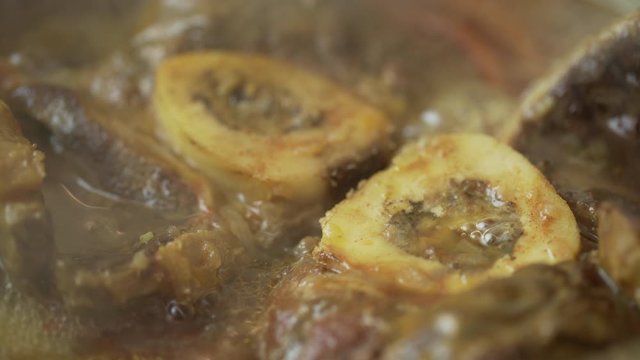 Closeup of delicious osso buco marrowbone cooked in a hot pan in a restaurant or in the kitchen of a house.