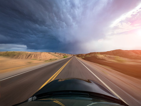 Car driving through a rural landscape toward a storm, United States
