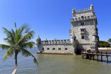 Scenic Belem Tower and wooden bridge miroring with low tides on Tagus River. Torre de Belem is...