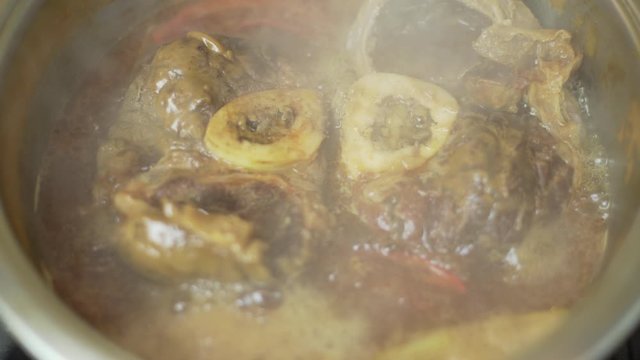 Closeup overhead shot of delicious osso buco marrowbone cooked in a hot pan in a restaurant or in the kitchen of a house.