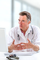 Online medical consultation: Doctor expplaining diagnosis while sitting in hfront computer with patient