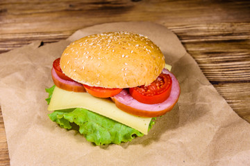 Fresh hamburger on brown paper on wooden table