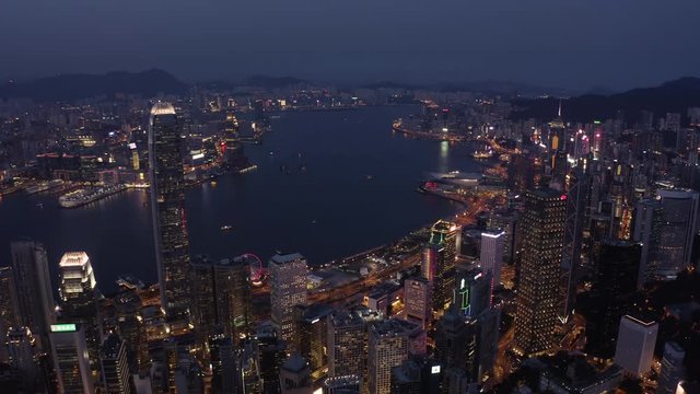 Bird eyes view of Hong Kong cityscape from the drone at night time. Tight aerial forward shot flying over office buildings and skyscrapers.