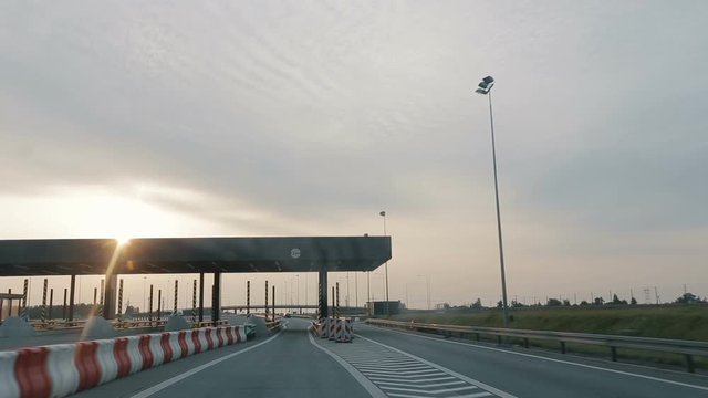 POV driving along a wide empty morning road early in the morning during sunrise.. Point of view driving, view from inside the car on on the autobahn in Poland. Entry or exit to a toll road section.