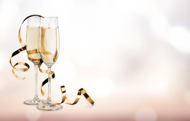 Glasses of champagne with curly ribbon on bright background