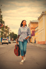 beautiful woman with a guitar walking down the street