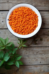 sea buckthorn berries in a white basin on a wooden floor.