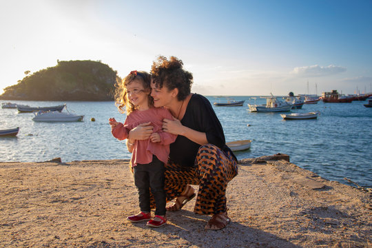 Smiling woman hugging her daughter on the beach, Armacao dos Buzios, Rio de Janeiro, Brazil, 