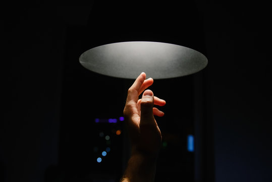 Man's hand reaching towards a ceiling light