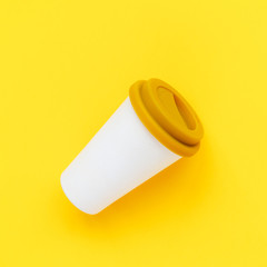 White bamboo coffee to go cup with a yellow rubber lid on a yellow background. Diagonal isometric view. Flat lay