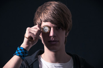 Blond boy with sweatshirt, showing a pocket watch with chain, photographed in studio with black background