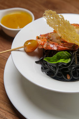 Black ink linguini pasta with roasted prawn skewer. Exquisite dish. Creative restaurant meal concept.	