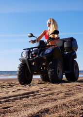 Obraz na płótnie Canvas attractive woman in bikini with long blonde hair is sitting on the quad bike, sunny day.