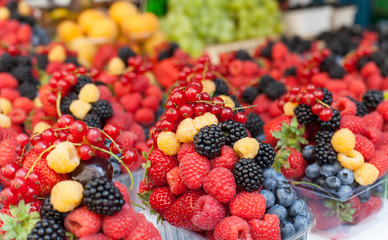 boxes with ripe berries and fruits laid out in a row at the market, store, close-up