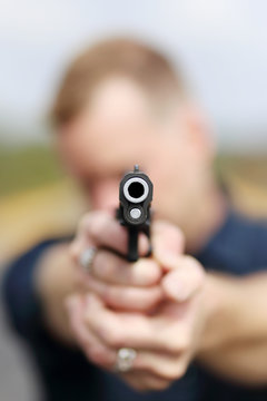 Closeup of a man aiming a pistol.