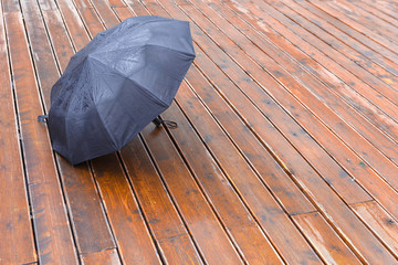 Black umbrella to dry on wooden floor