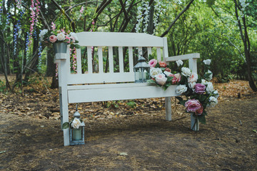 White bench in the garden in the autumn garden. A white bench standing alone in the garden.