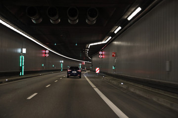 Tunnel with a black car and different signs and lights