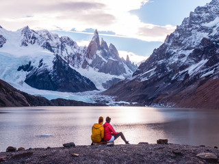 Couple on Patagonia hiking trek, looking at view of Snowcapped peaks of Cerro Torre, with lake foreground. Mountains, nature, travel. Shot in El Chalten, Laguna Torre, Mount Fitzroy, Argentina