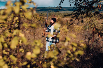 Hunter with shotgun gun on hunt. Hunter in the fall hunting season.