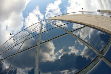 A blue sky with white clouds reflecting from a tile wall of a modern building