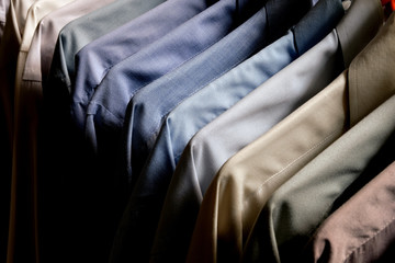 Obraz premium Classy, stylish, colorful men's formal long sleeve shirts neatly arranged and organized in a row on a clothes rack hanger for quality choice selection.