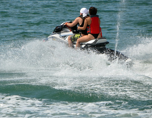 Young couple riding tandem on a speeding jet ski