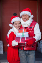 Couple holding gifts dressed in holiday attire