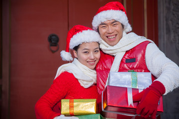 Couple holding gifts dressed in holiday attire