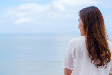 Obraz premium A beautiful asian woman standing back by the sea