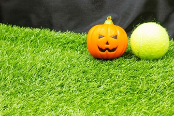 Obraz premium Tennis halloween with tennis ball and pumpkins are on green grass