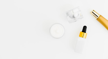 White serum bottle and cream jar, mockup of beauty product brand. Top view on the white background.