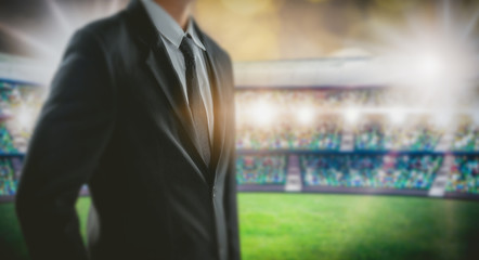 Manager leadership concept, businessman in black suit stand at soccer stadium in background.