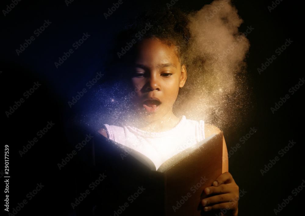 Wall mural surprised african-american girl reading magic book on dark background