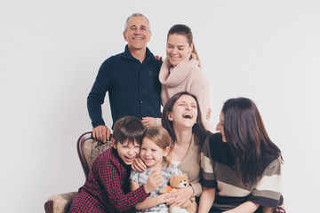 concept of happy childhood, family, love - group of people on a white background: adults and children with toys sitting on the same couch
