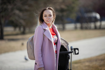 Young woman with a pram in a city park.