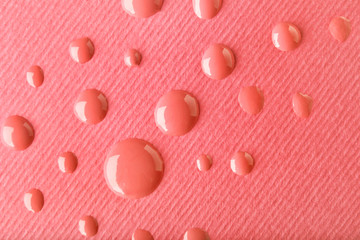 Drops of nail polish on pink paper, closeup