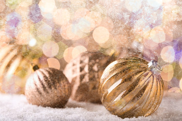 Christmas baubles on snow against blurred lights