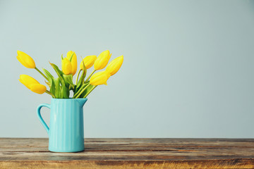 Jug with beautiful tulips on wooden table