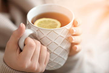 Beautiful young woman with cup of hot tea, closeup