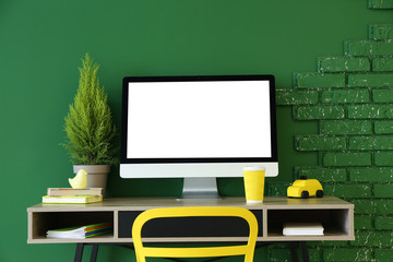 Stylish workplace with modern computer near green wall at home