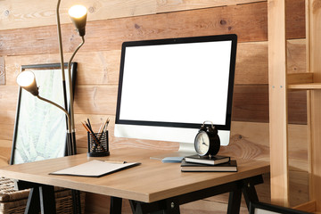 Stylish workplace with modern computer near wooden wall at home