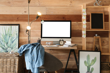 Stylish workplace with modern computer near wooden wall at home