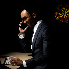 Business man talks to client and hand on computer keyboard in late night, work hard to achieve 120%...